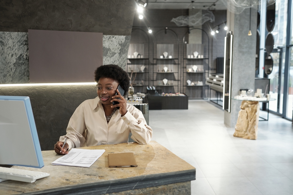 Female employee of jewelry boutique consulting clients sitting at the table