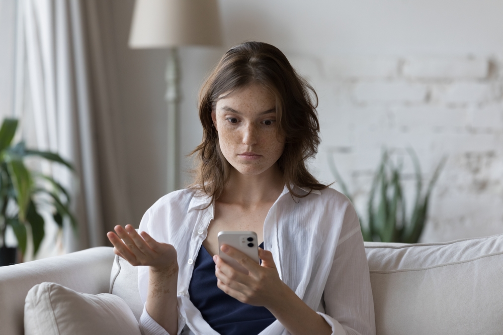 Shocked concerned girl looking at smartphone screen, getting surprising bad news