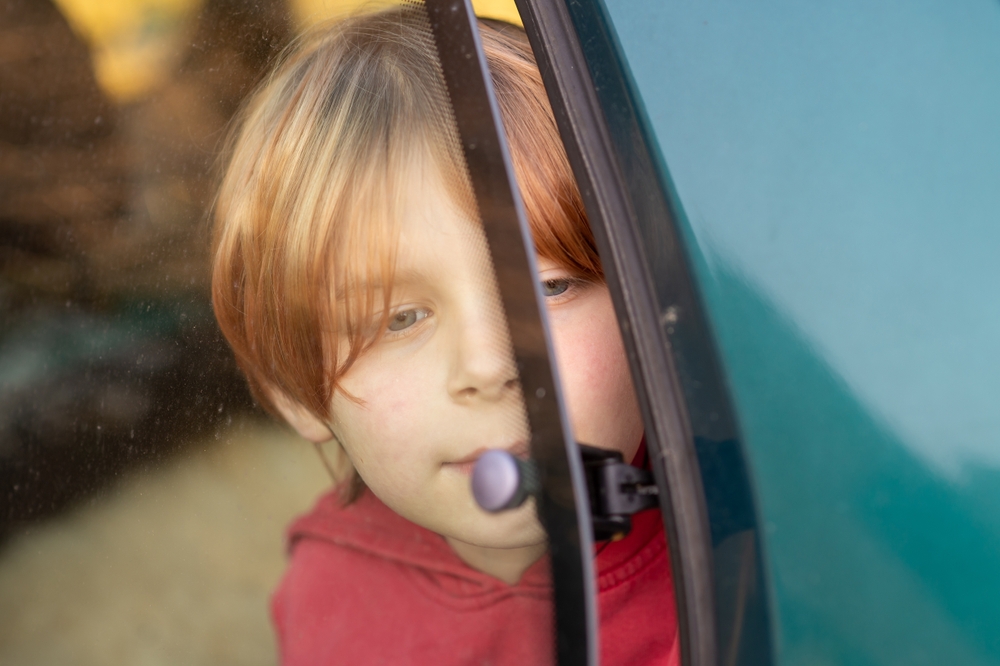 Young boy in front of a car window