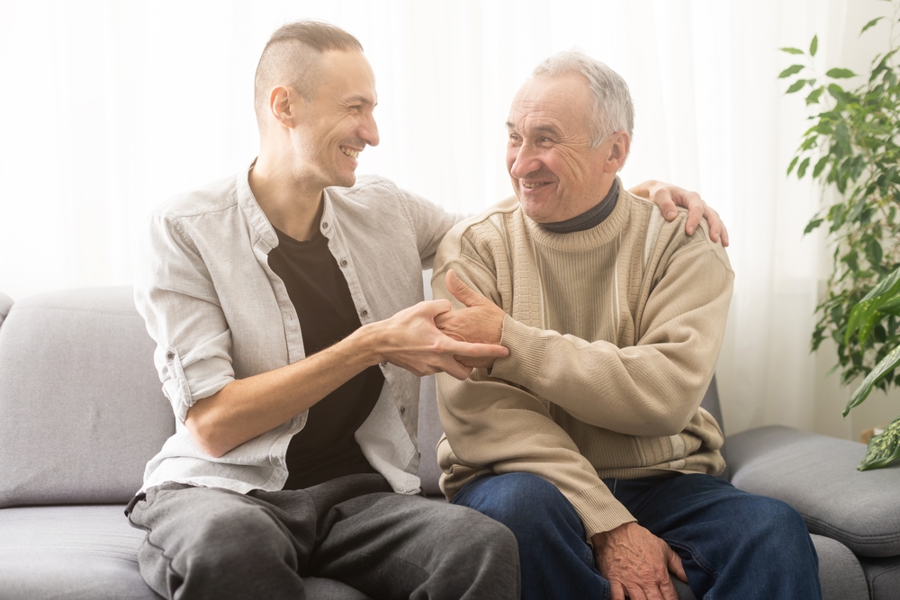 Young and older men sitting on a couch at home