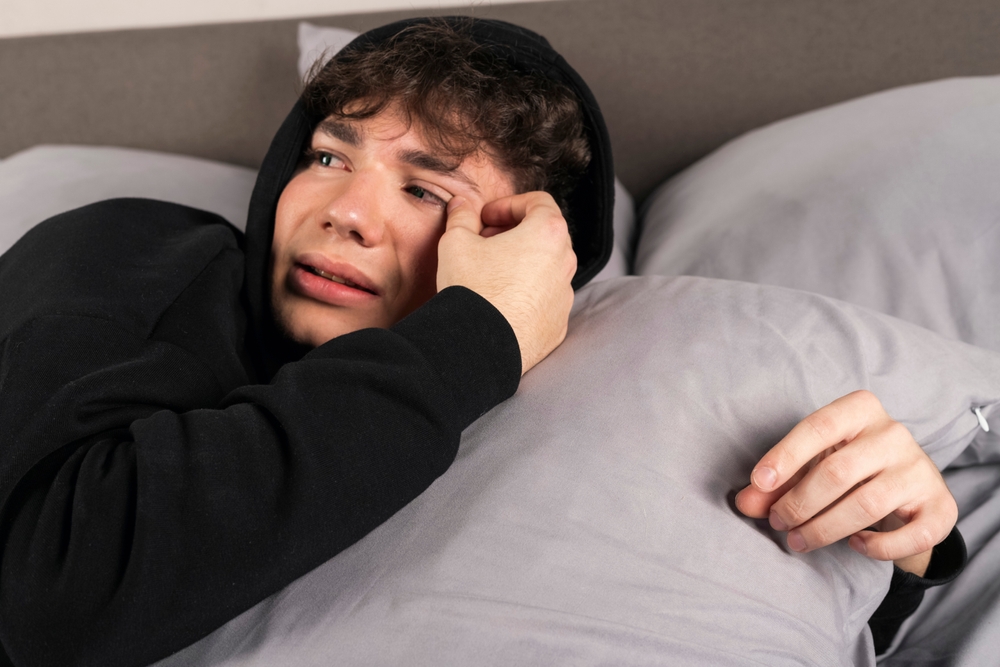 Scared teenager woke up of sleep with hands under pillow 