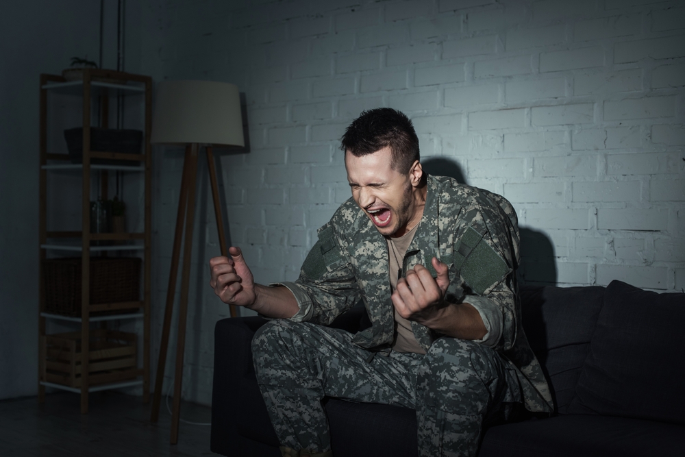 Shocked soldier sitting on a couch at home