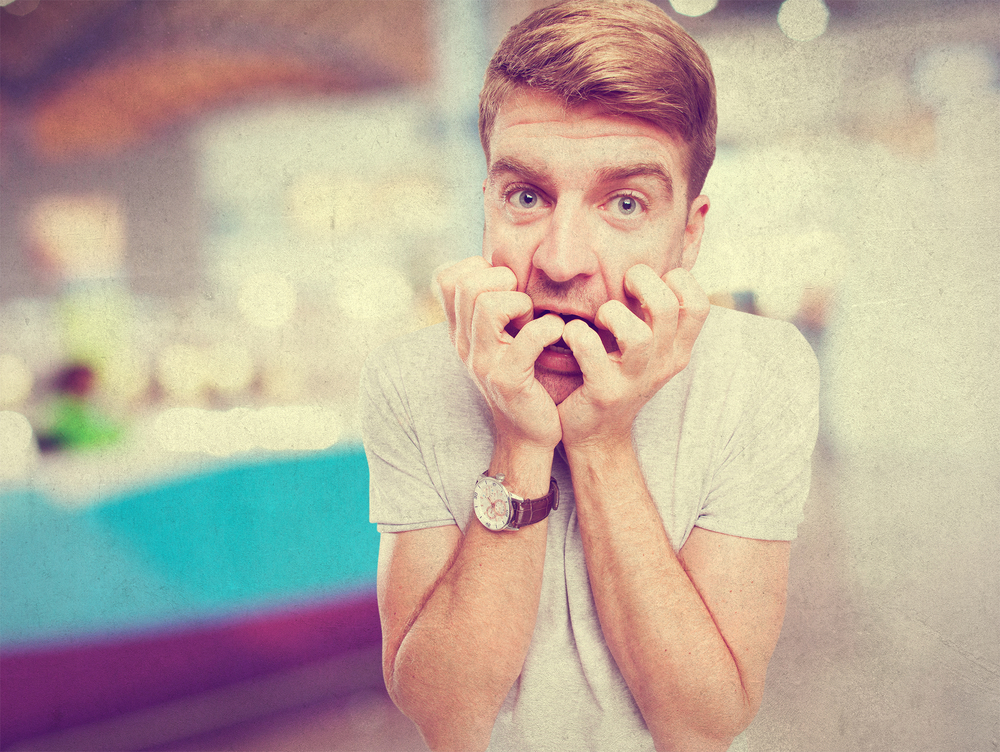 Scared grossed out man with hands in mouth