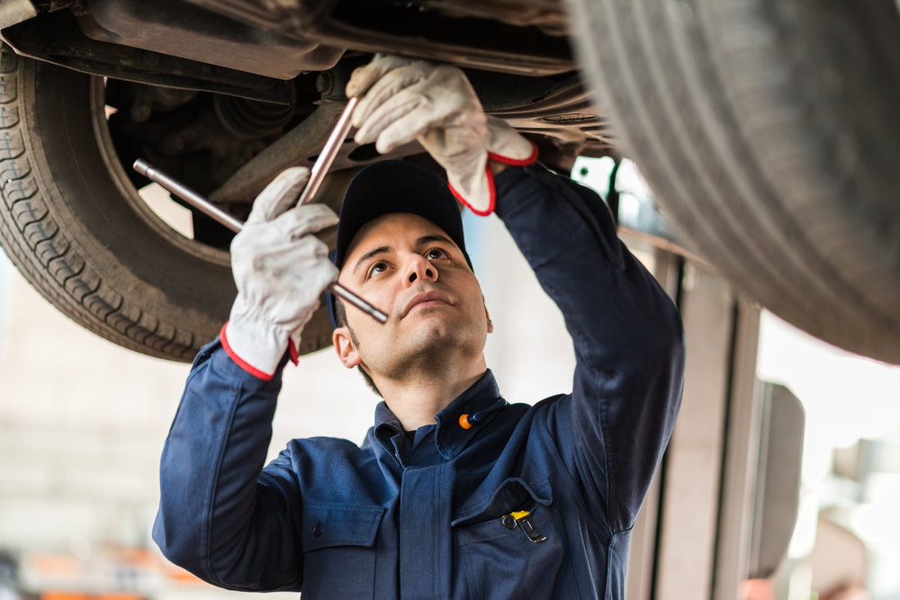 Portrait of a mechanic repairing a lifted car