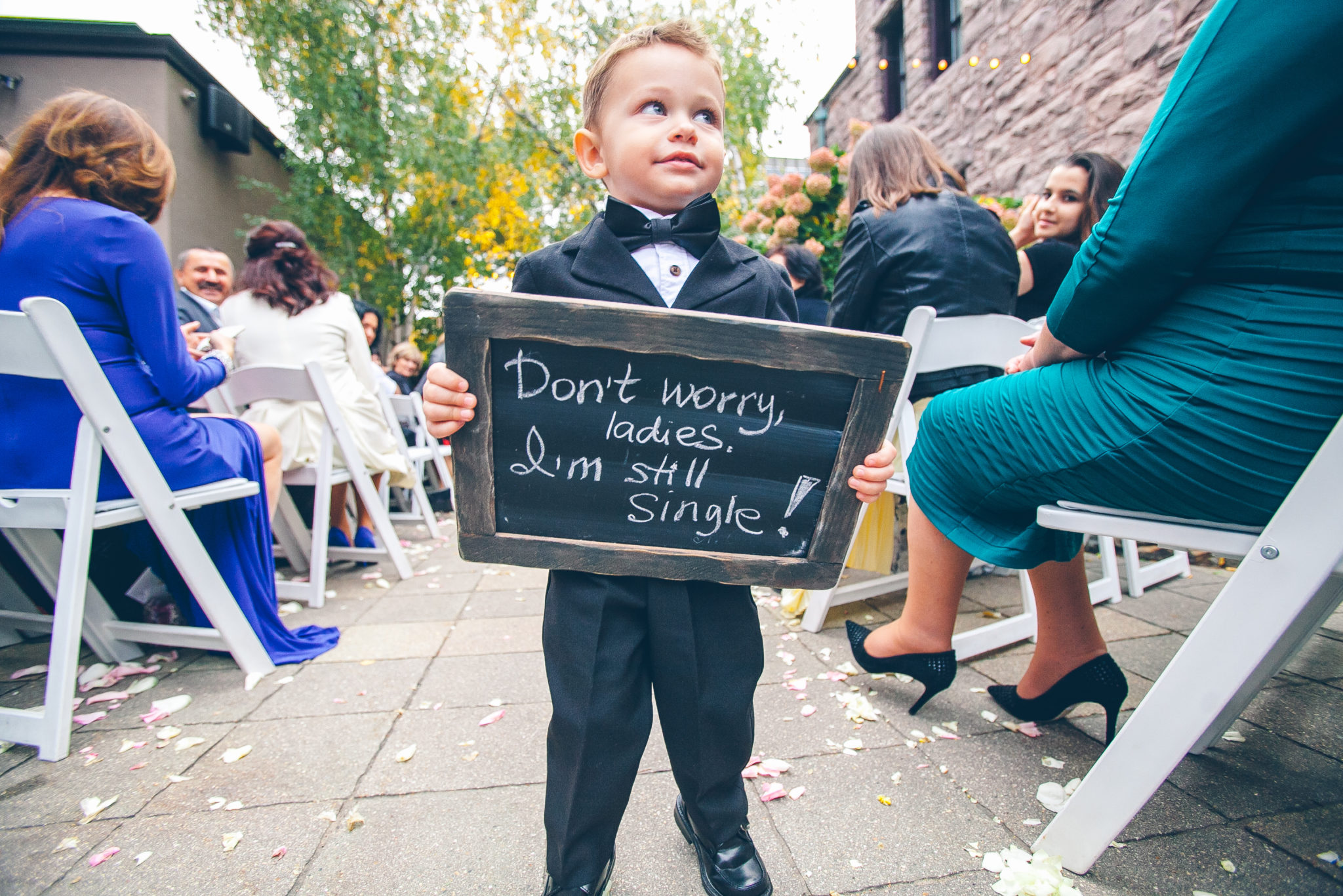 Boy in a black suit, is holding a blackboard