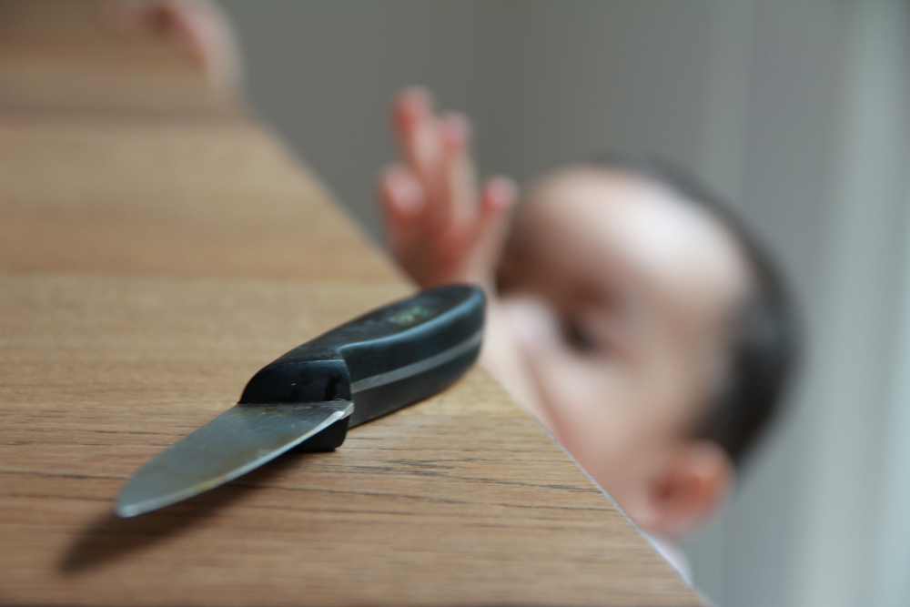 Toddler reaching to grab a kitchen knife left on a counter 