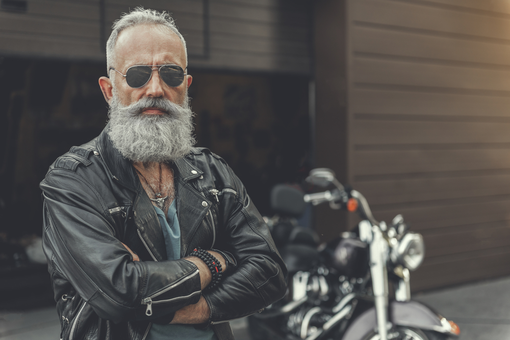 Older biker man standing in front of his bike