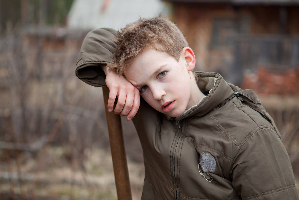 Teen boy in dark jacket holding a shovel