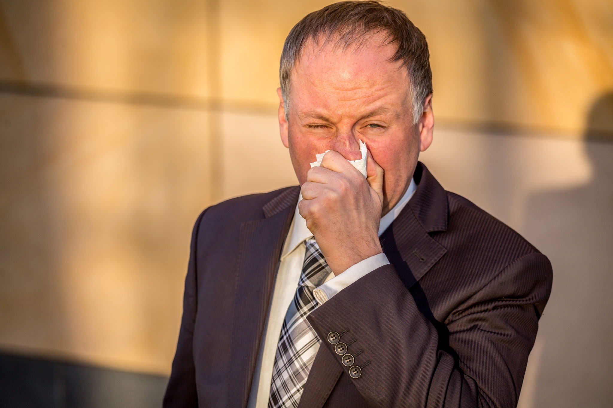 Man sneezing in his hand