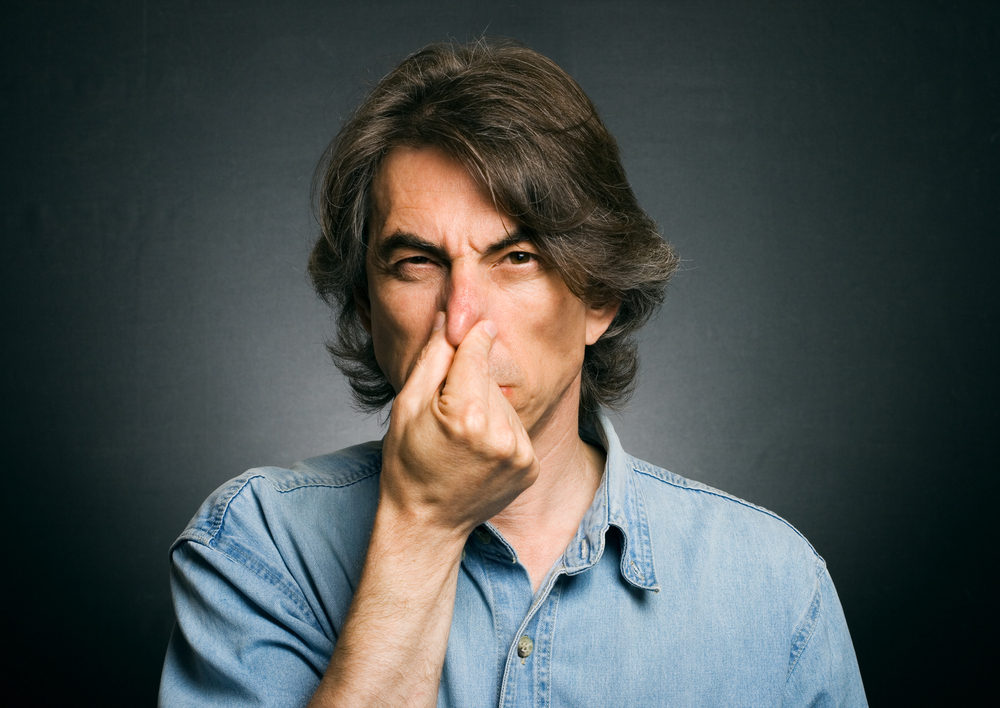 Man holding his nose because of bad smell