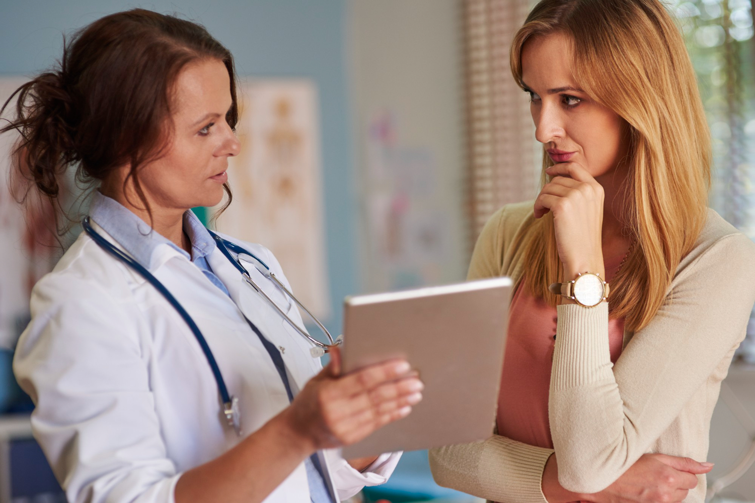 Female doctor is talking with female patient at hallway.