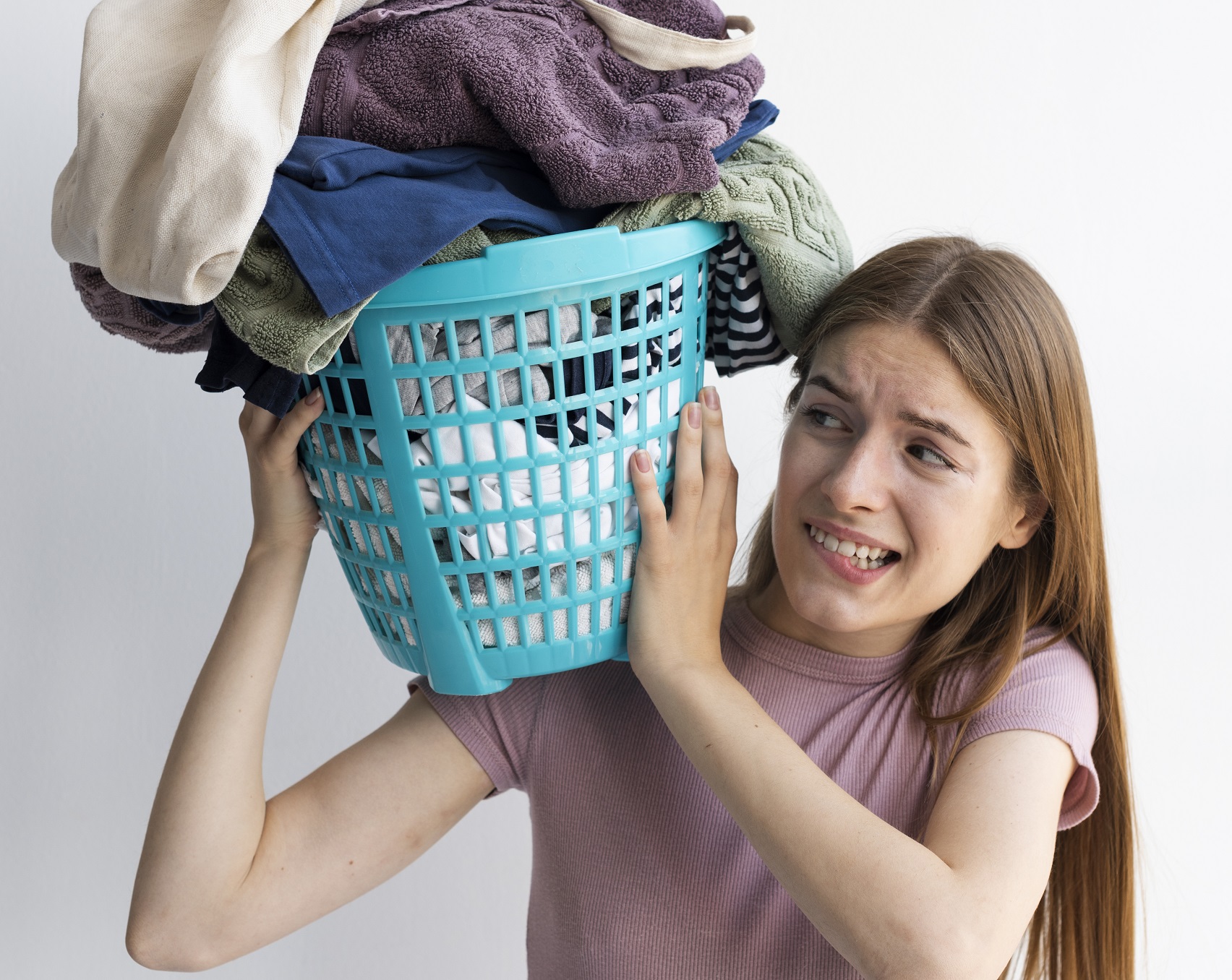 Woman holding a basket of clothes on her shoulder.