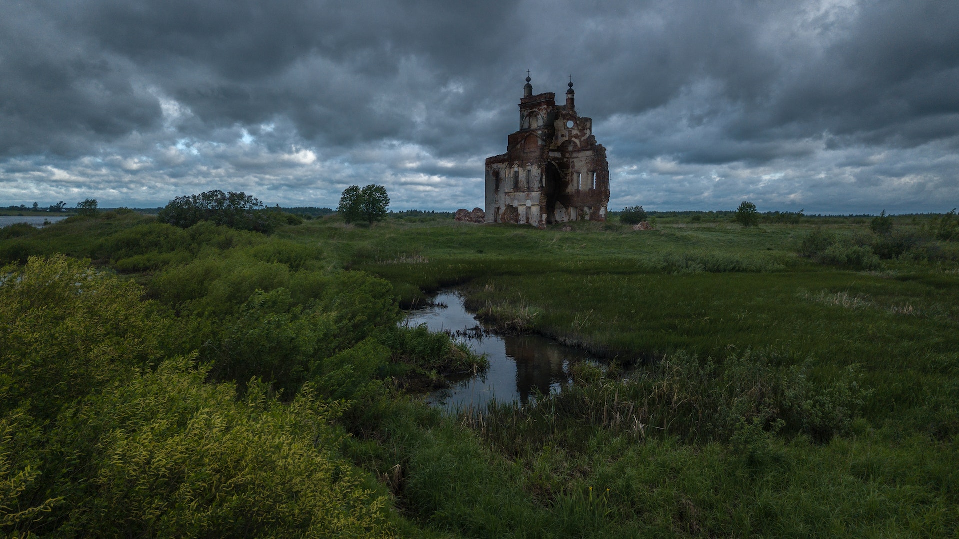 ruins of church in marshland surrounded by swamp and green grass