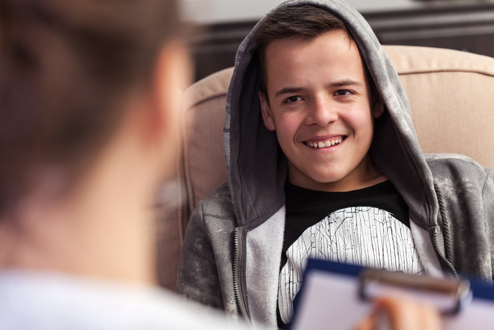 Young boy in counseling session at the psychologist or social services professional, laughing