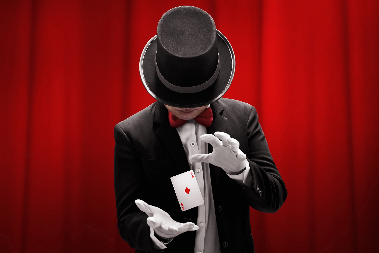 Magician hands showing magic trick on red background.