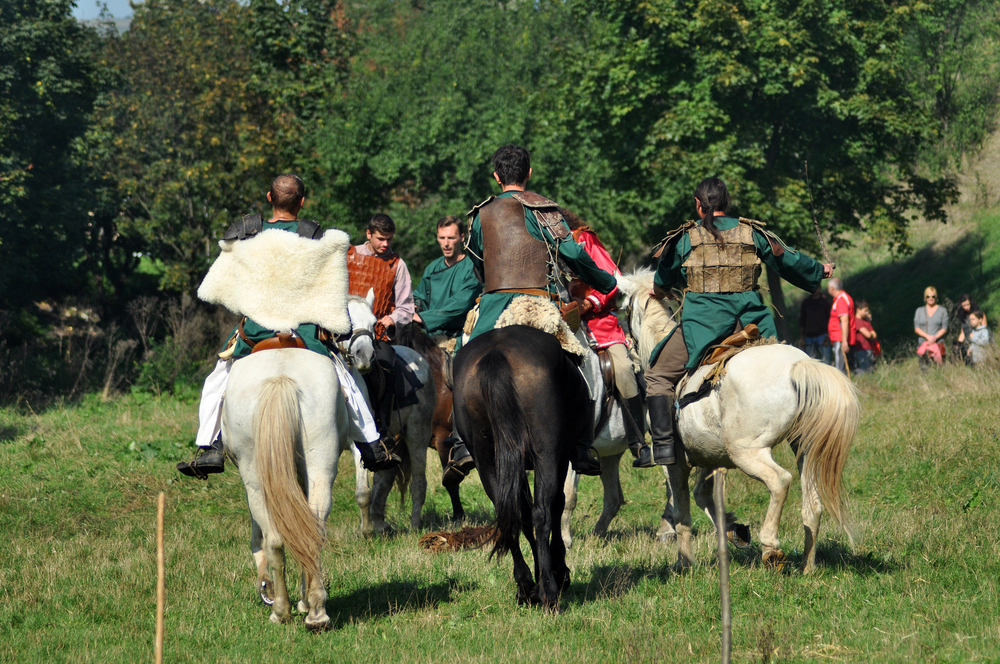 people riding black and white horses wearing archaic costumes