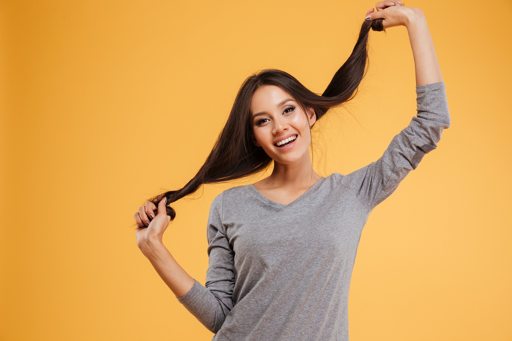 Attractive woman holding to the hair on orange background.