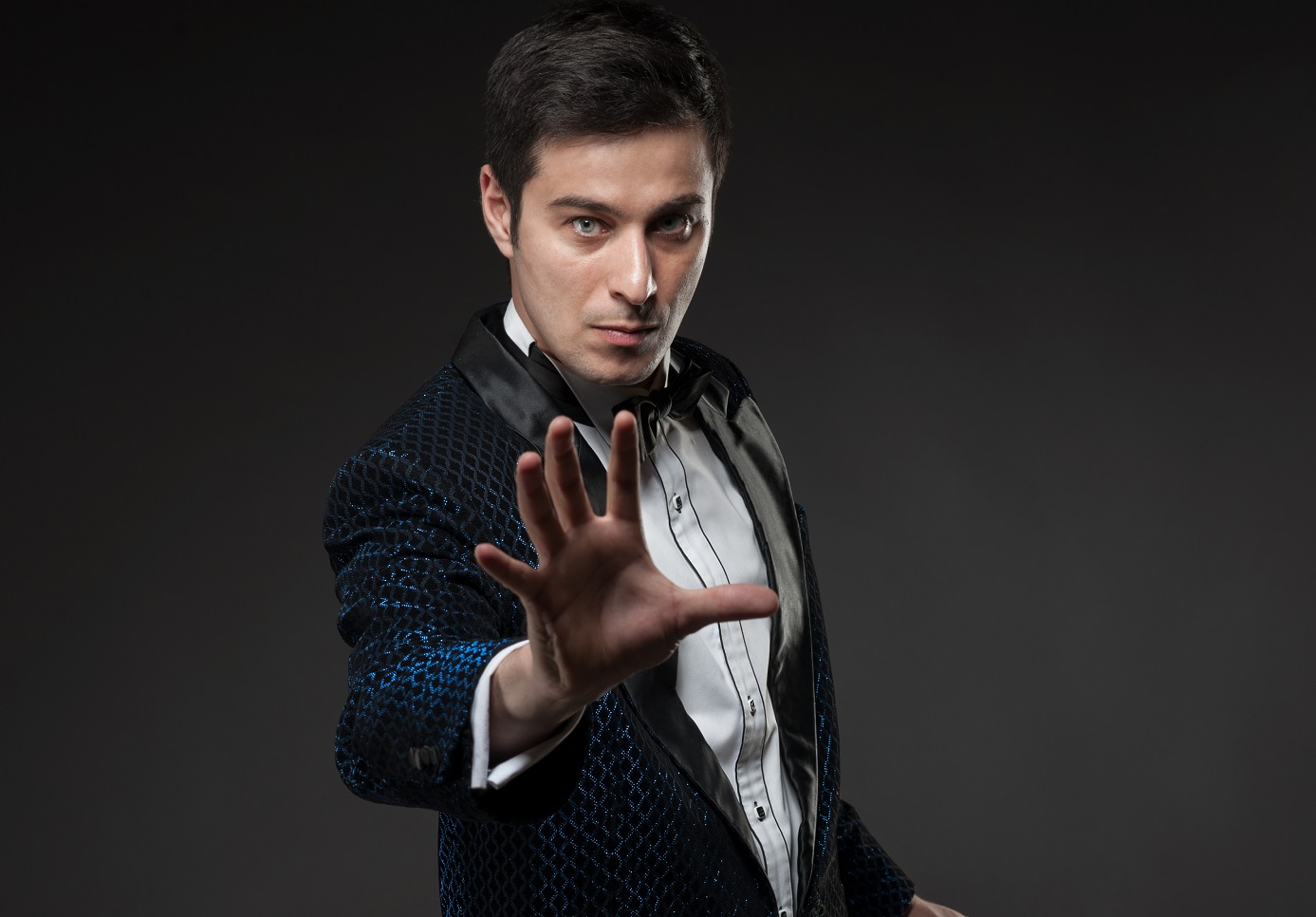 Happy magician wearing suit is looking at camera.