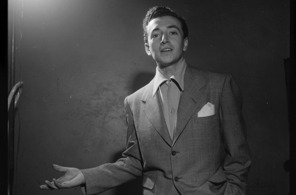 Grayscale portrait photo Of Vic Damone with his left hand raised