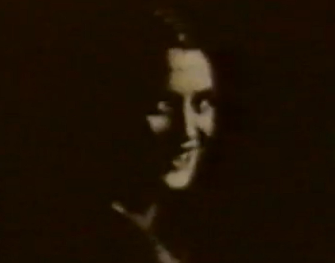 Screenshot: B&W Lee Miller looking and smiling at camera at dark background - from Lee Miller: Through the Mirror (1955)