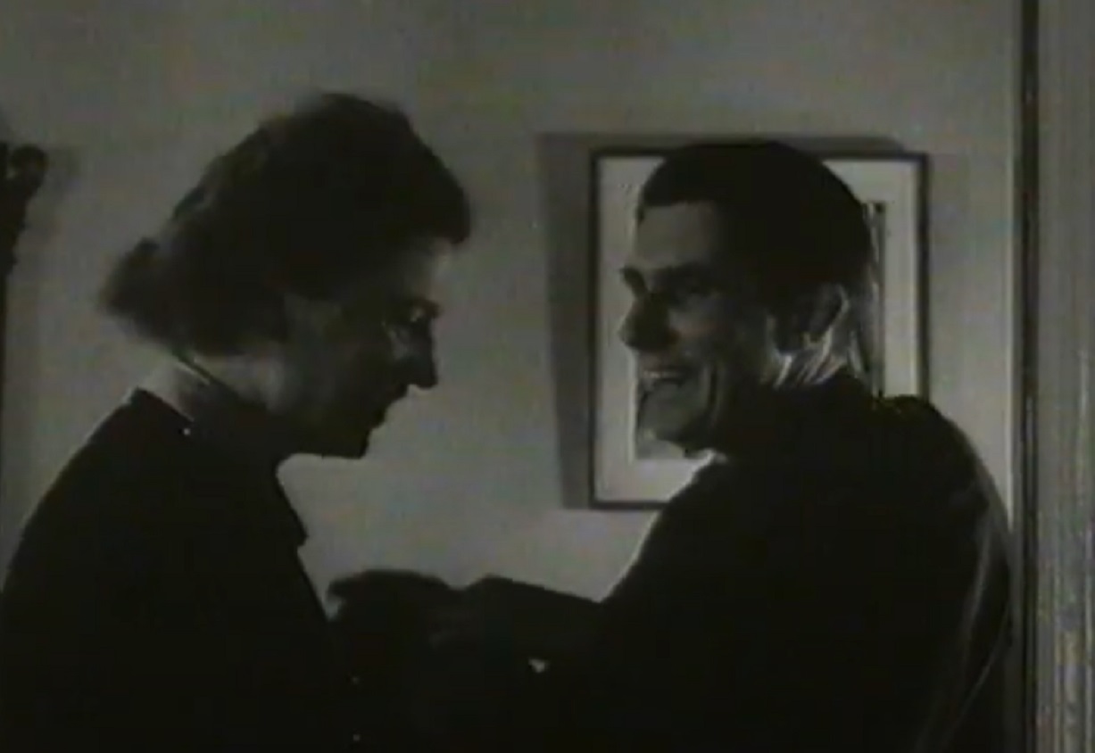 Screenshot: B&W Lee Miller is standing next to Roland Penrose and smiling - from Lee Miller- Through The Mirror (1955)