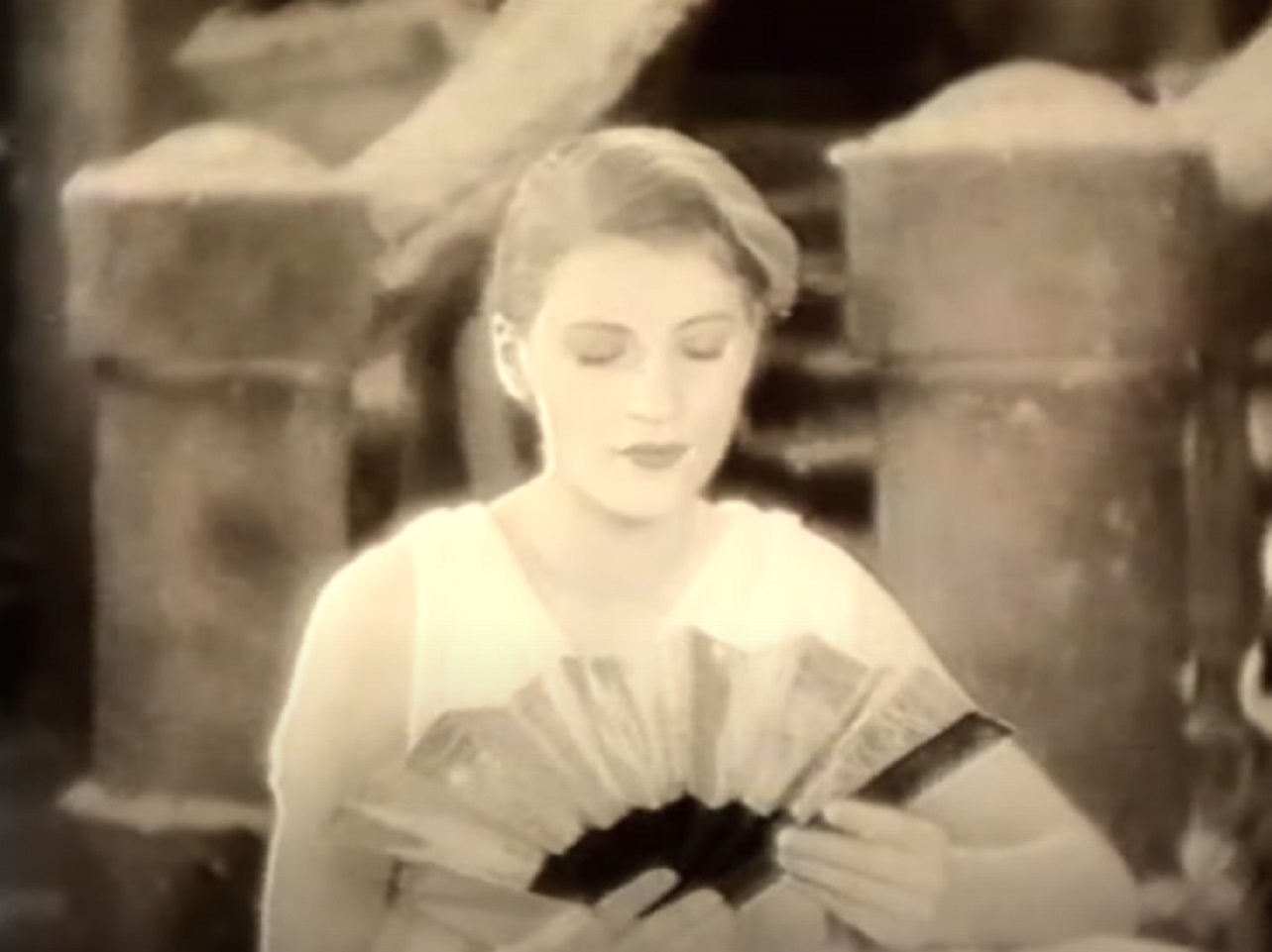 Screenshot: B&W Lee Miller wearing white dress is looking down - from Lee Miller: Through the Mirror (1955)