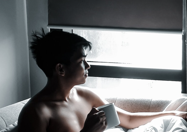 Man is seating on the couch and drinking coffee.