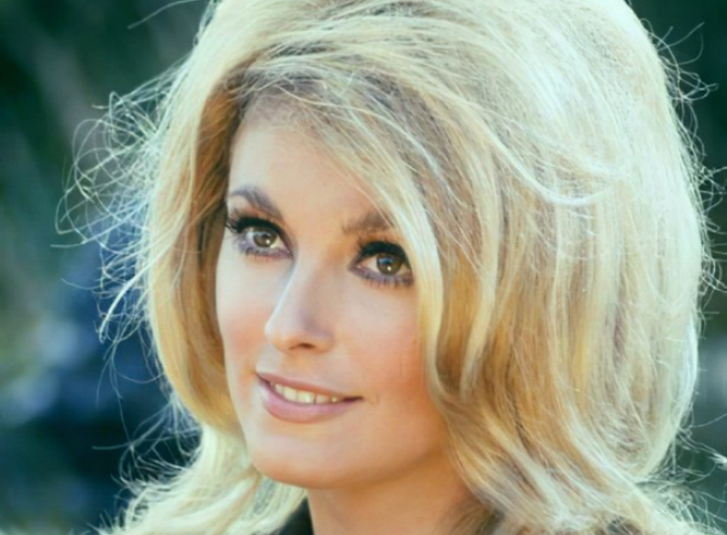 Sharon Tate in black top looking at the camera