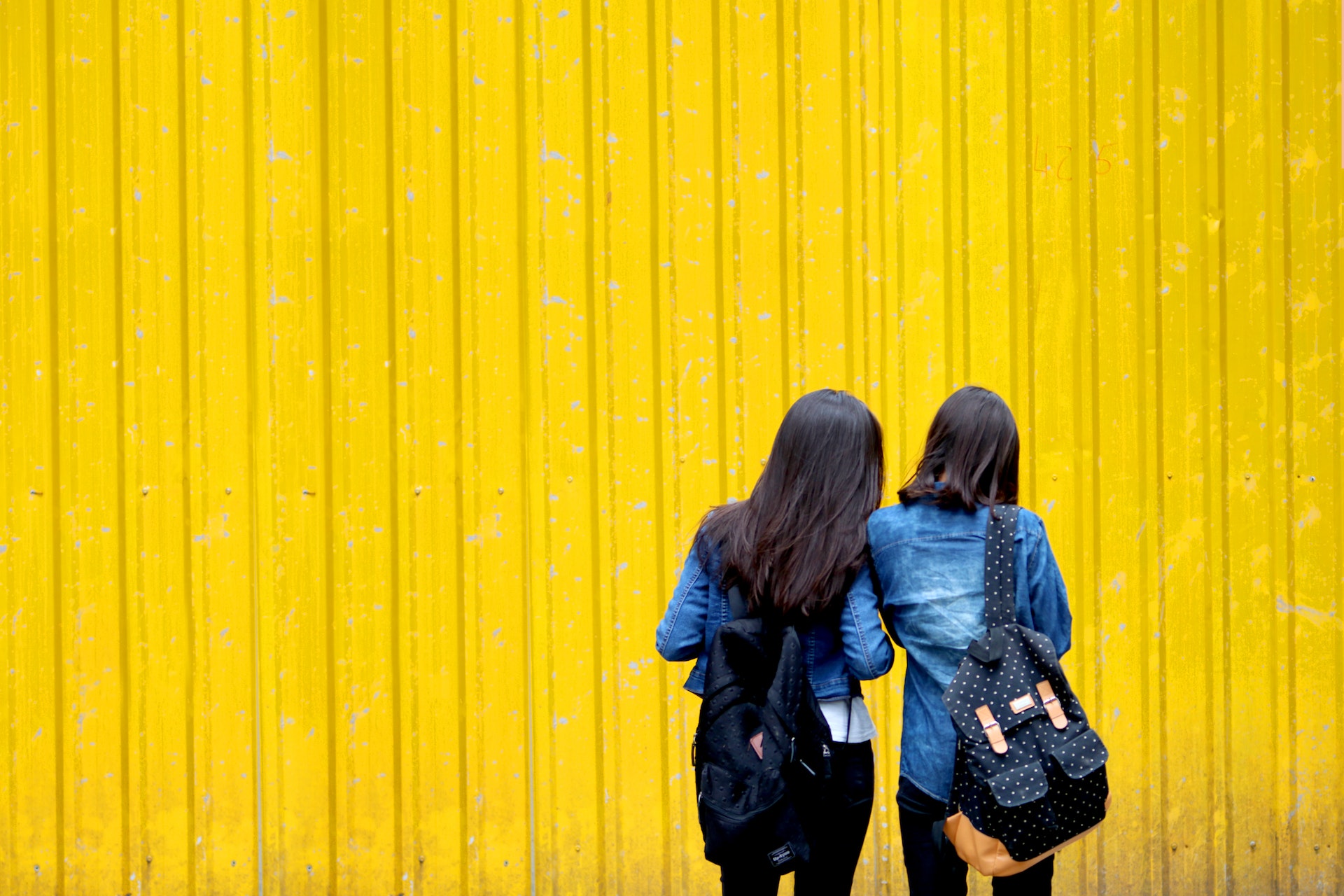 Two girls looking at yellow wall