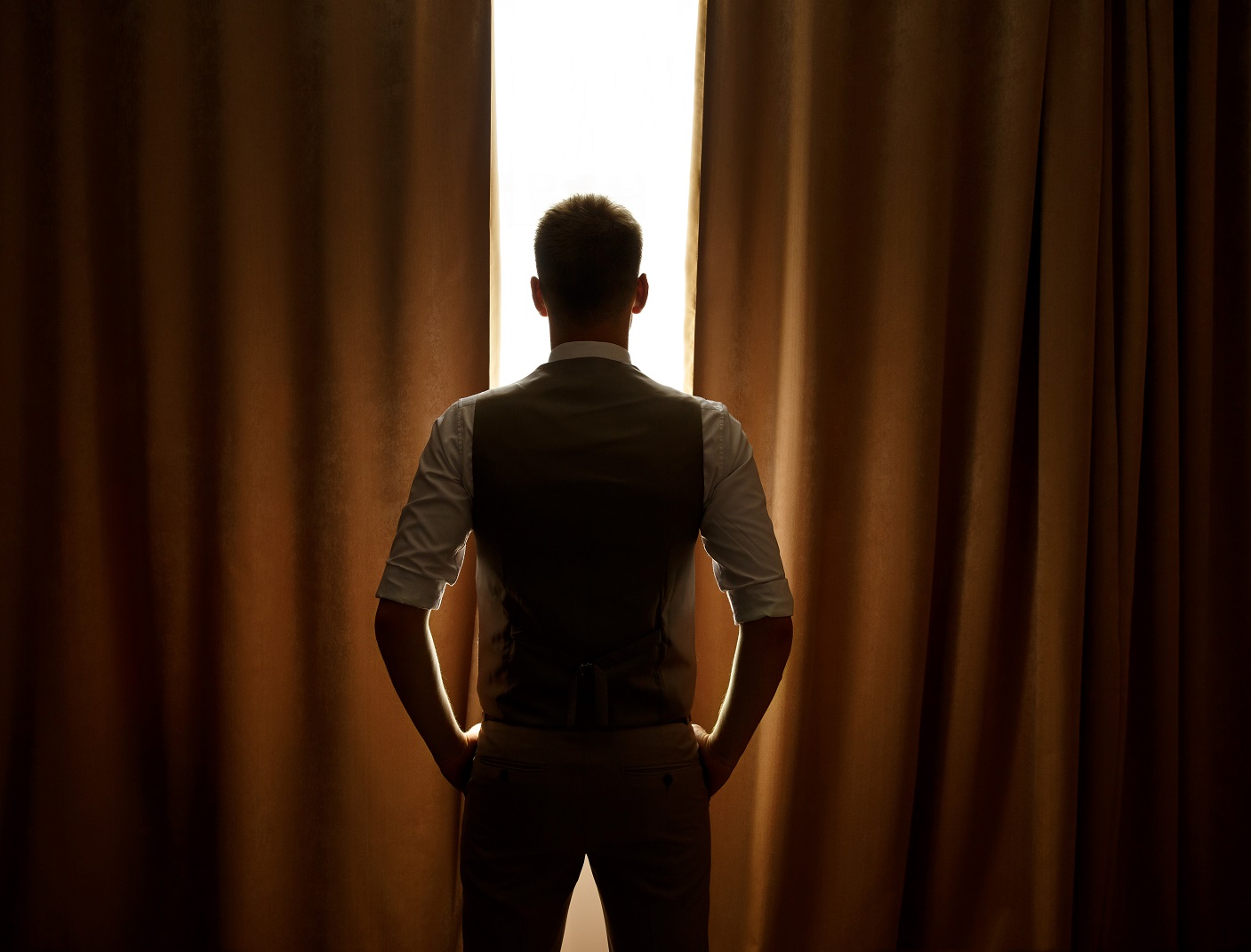 Silhouette of man standing in front of a window.