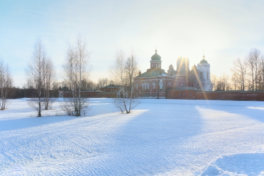 Winter landscape of a Russian Monastery in the rays of the winter sun with a snow field