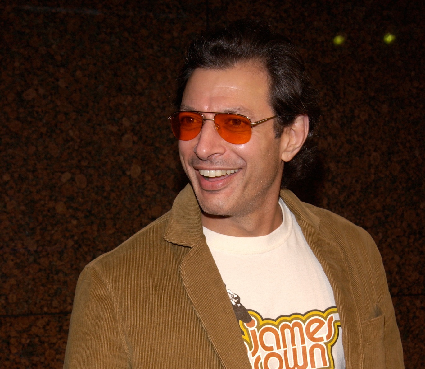 Jeff Goldblum wearing brown jacket and orange glasses is smiling - 2001