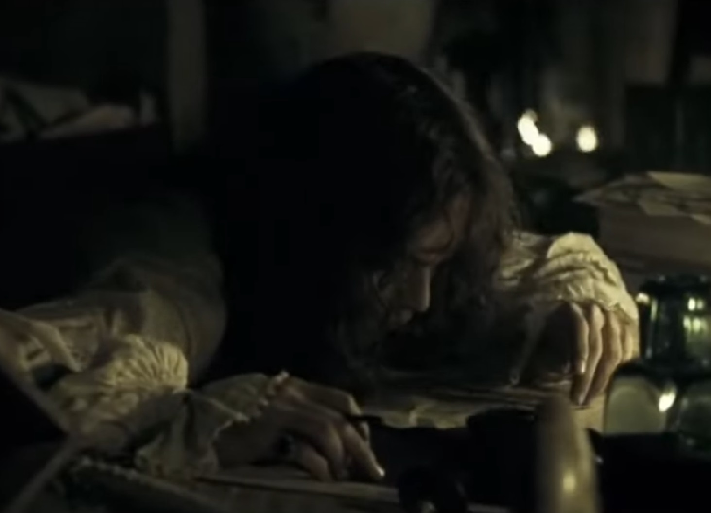 Screenshot: Johnny Deep with long hair is standing over the desk in the room  - from The Libertine (2004)