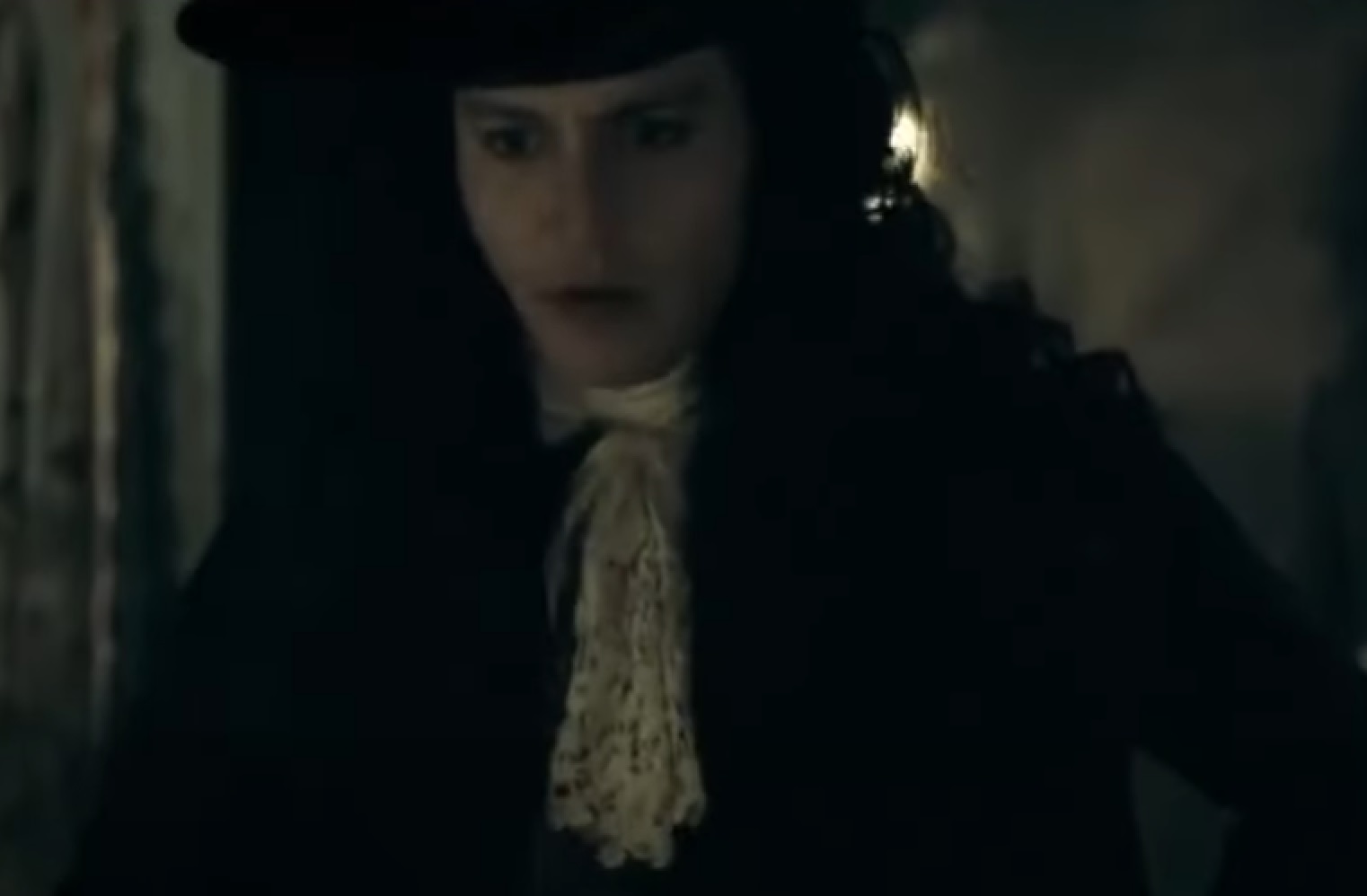 Screenshot: Johnny Deep with long hair wearing black shirt and white scarf is looking down - from The Libertine (2004)