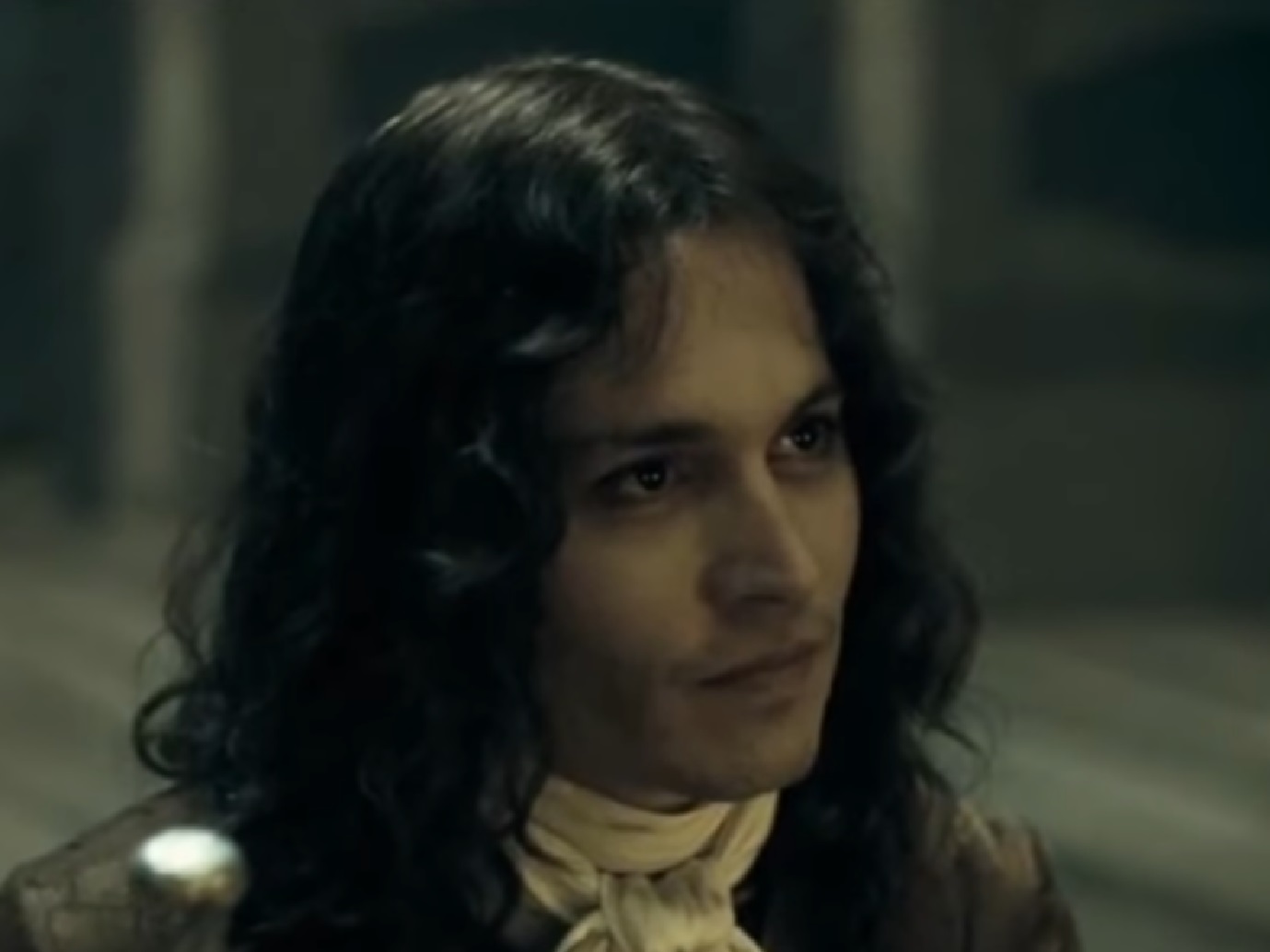 Screenshot: Johnny Deep with long hair wearing black shirt and white scarf is looking at side - from The Libertine (2004)