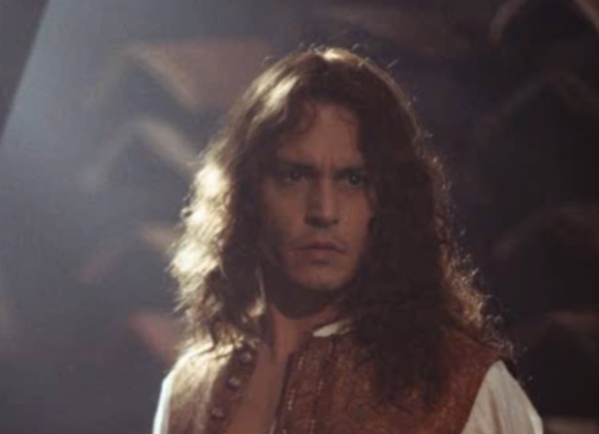 Screenshot: Johnny Deep with long hair wearing white shirt and brown west is looking at side - from The Libertine (2004)