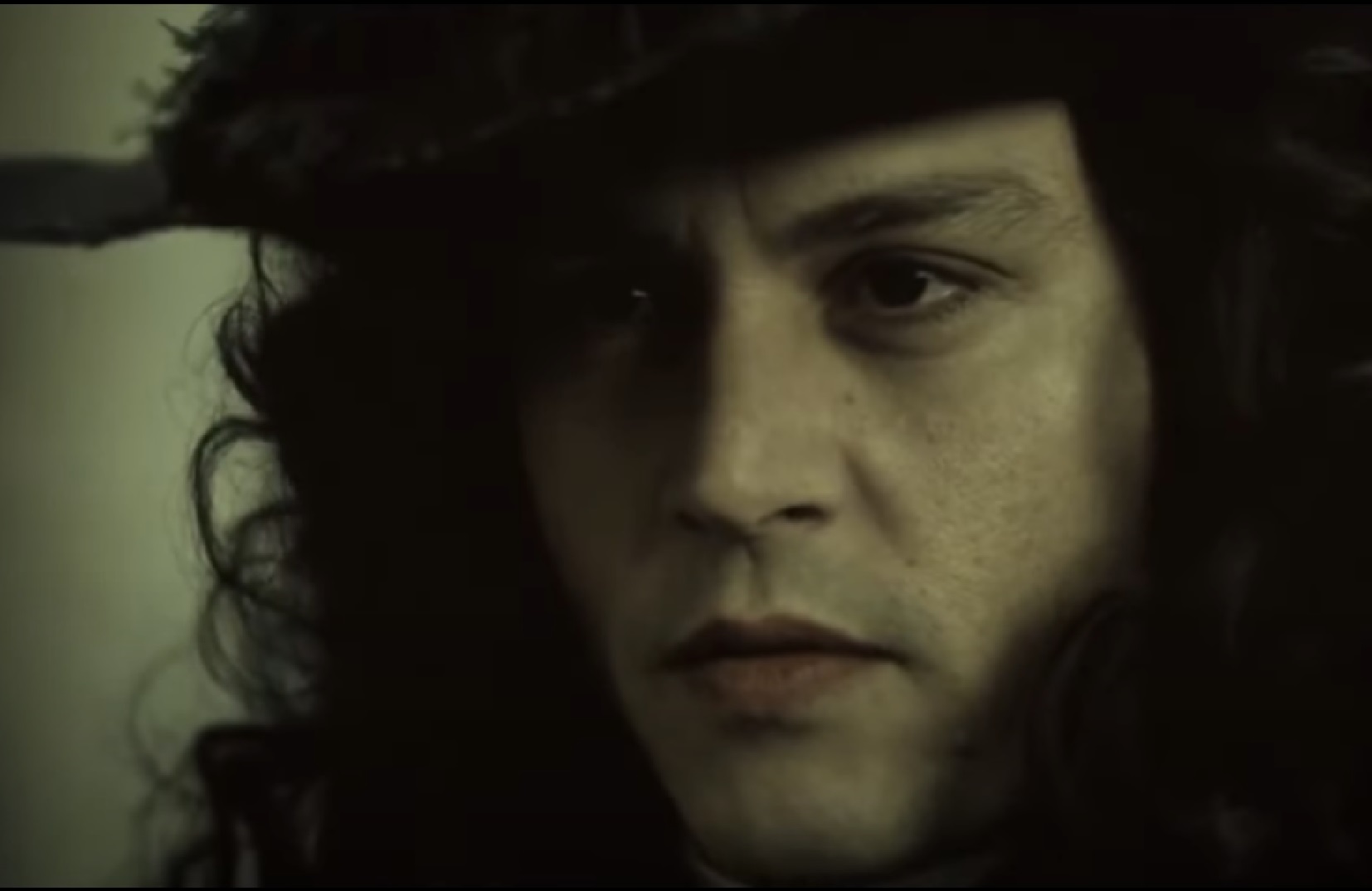 Screenshot: Johnny Deep with long hair wearing black hat is looking at side - from The Libertine (2004)