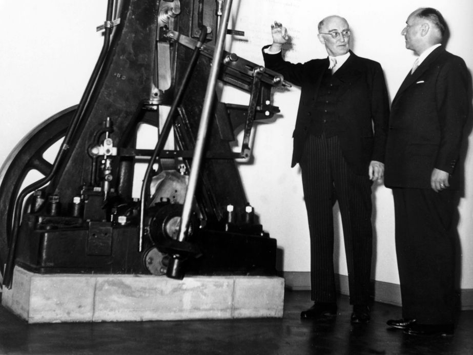 Eugen Diesel in suit speaking to Dr Hans Seidel