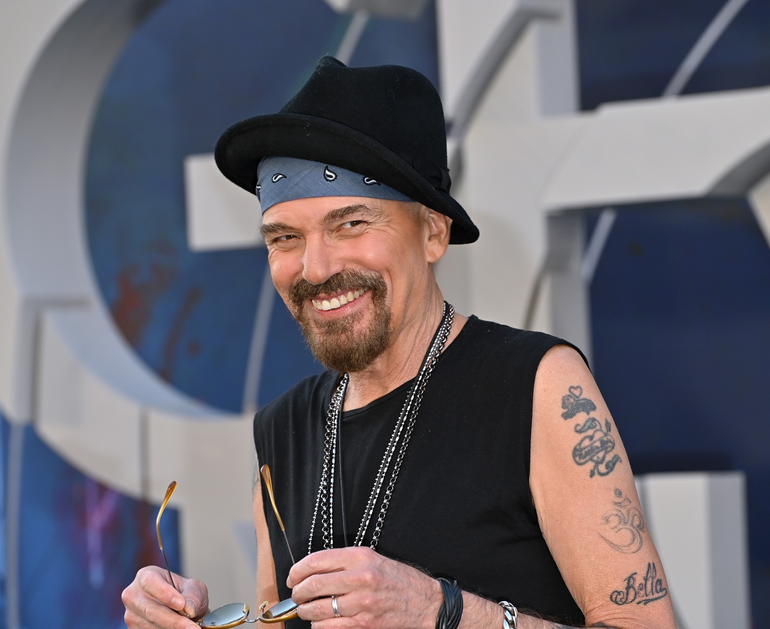 Billy Bob Thornton wearing black shirt and hat is smiling at camera - 2022