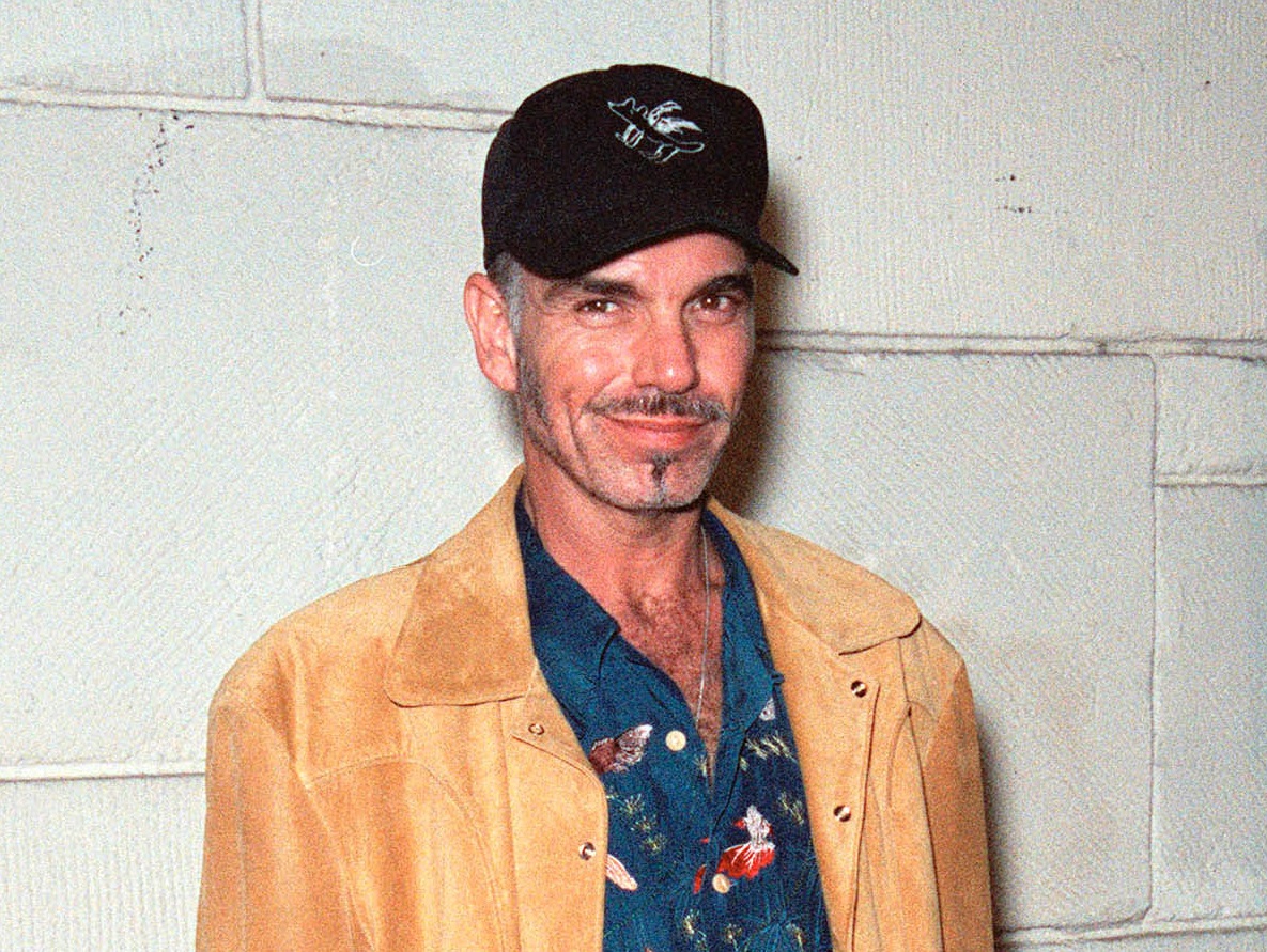 Billy Bob Thornton wearing hat and orange jacket is smiling at camera - 1999
