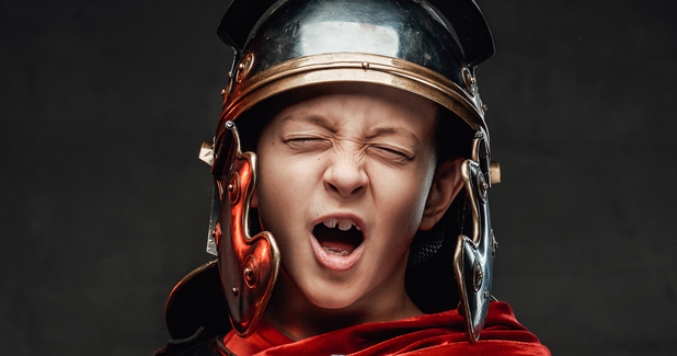 Expressive boy with sword dressed in dark armour with cloak