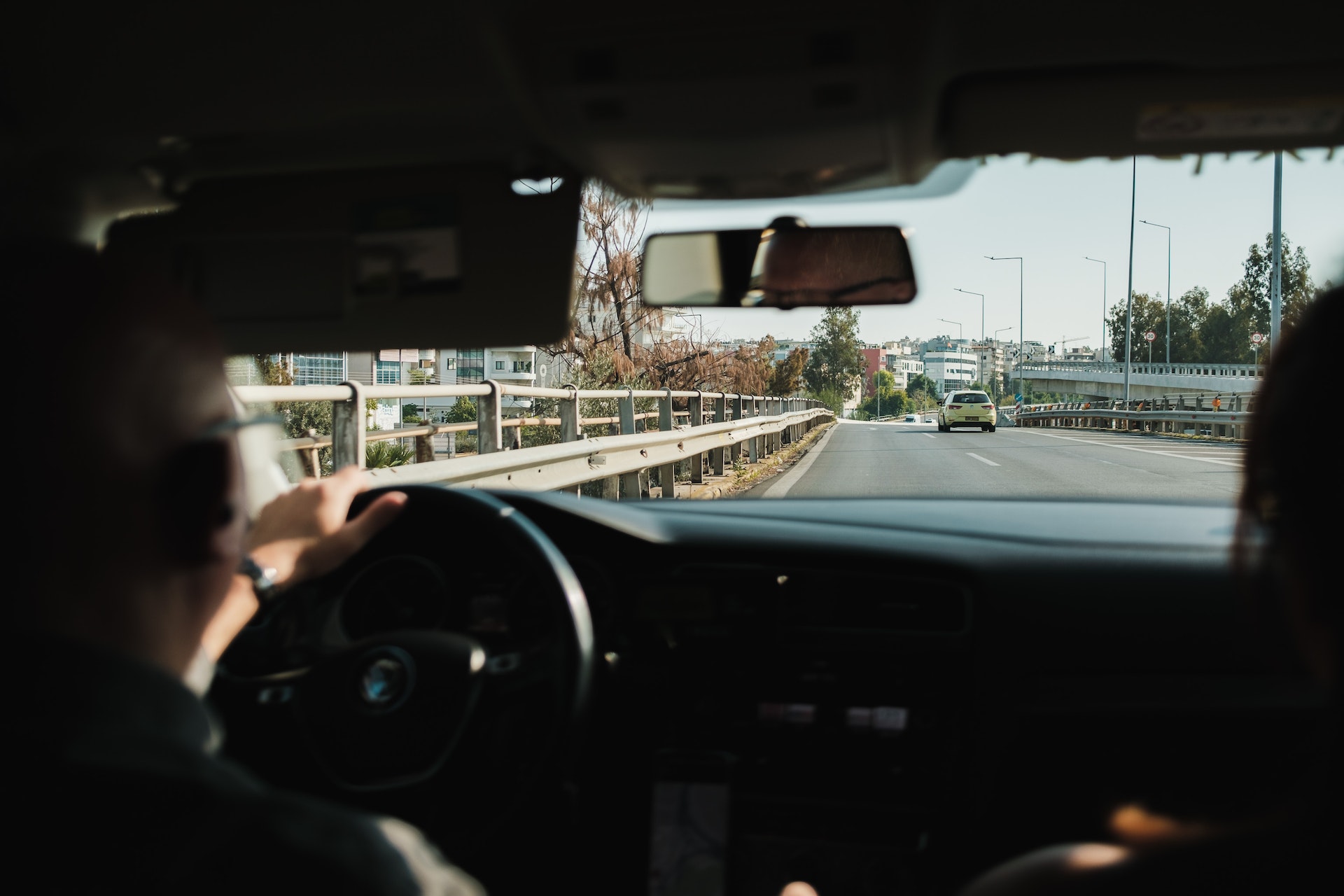 a man and woman driving in a car with a highway in front