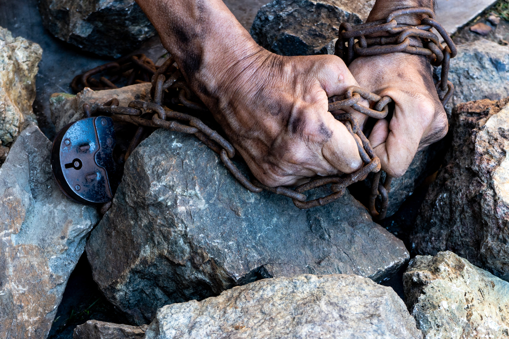 The hands of a slave in an attempt to release placed on rocks.