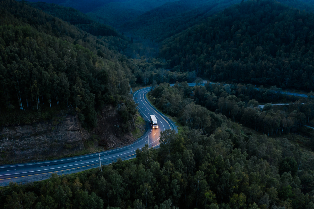 Semi truck on a dark highway in forest at night