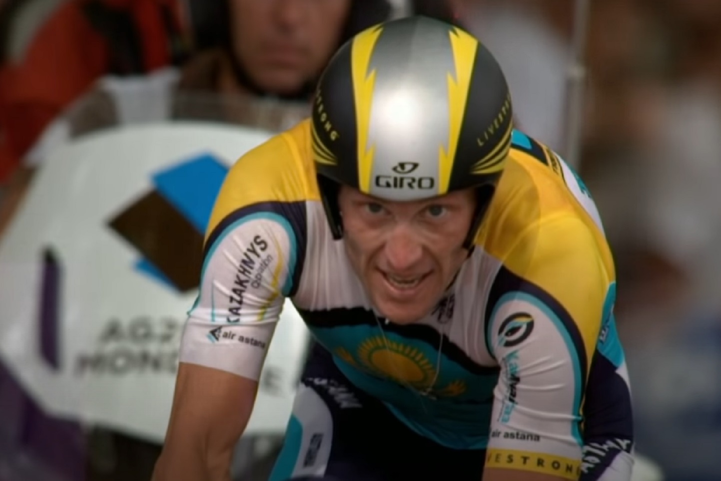 Screenshot: Lance Armstrong wearing shirt and helmet is cycling -from The Armstrong Lie (2013)
