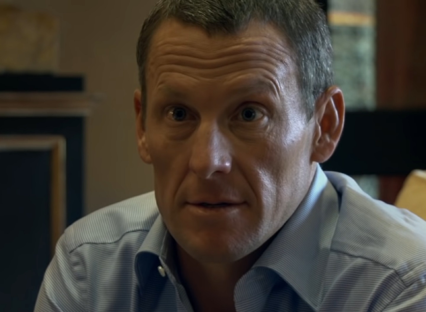 Screenshot: Lance Armstrong wearing blue shirt is looking at camera - from The Armstrong Lie (2013)