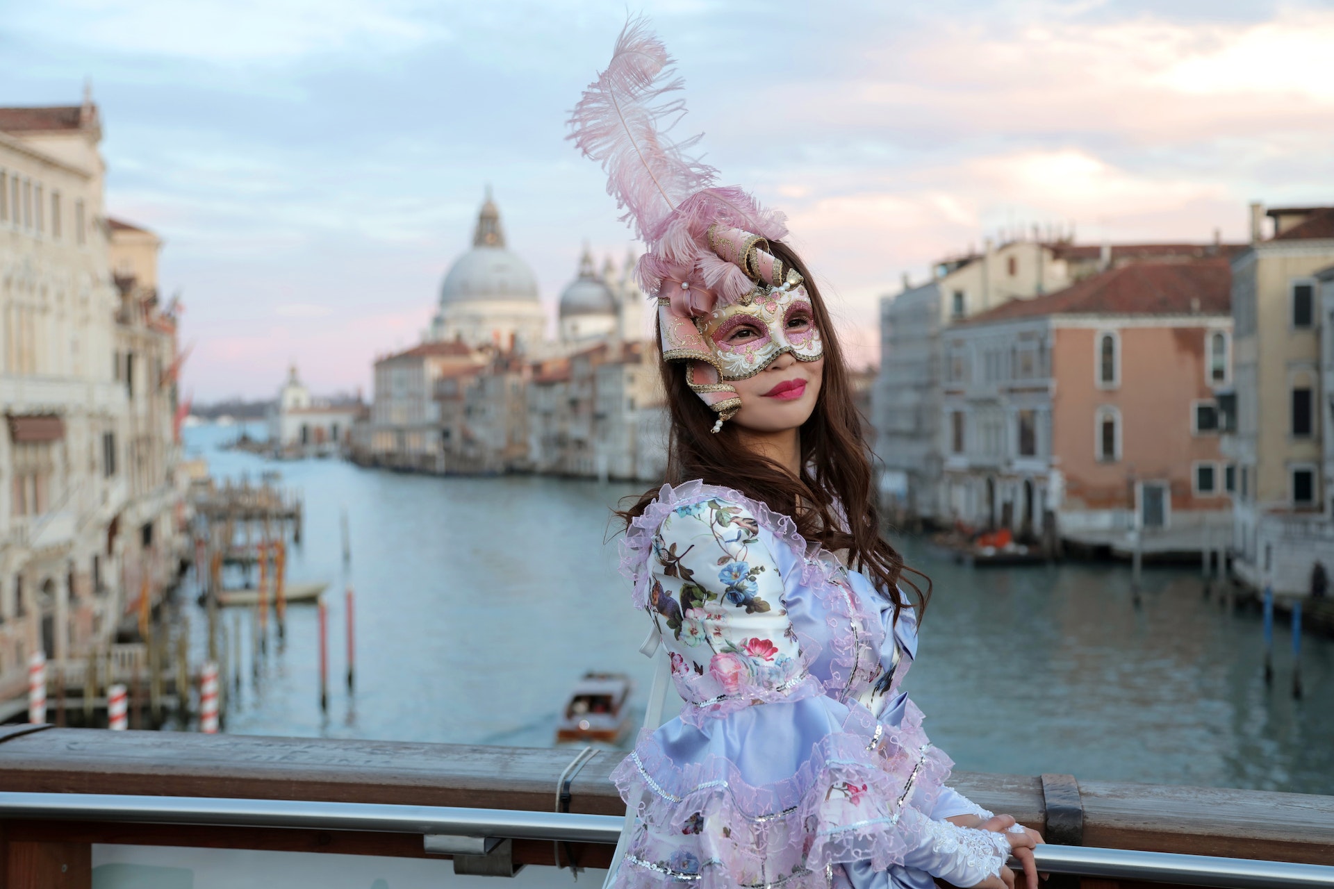 woman in colorful venetian clothes and mask on bridge