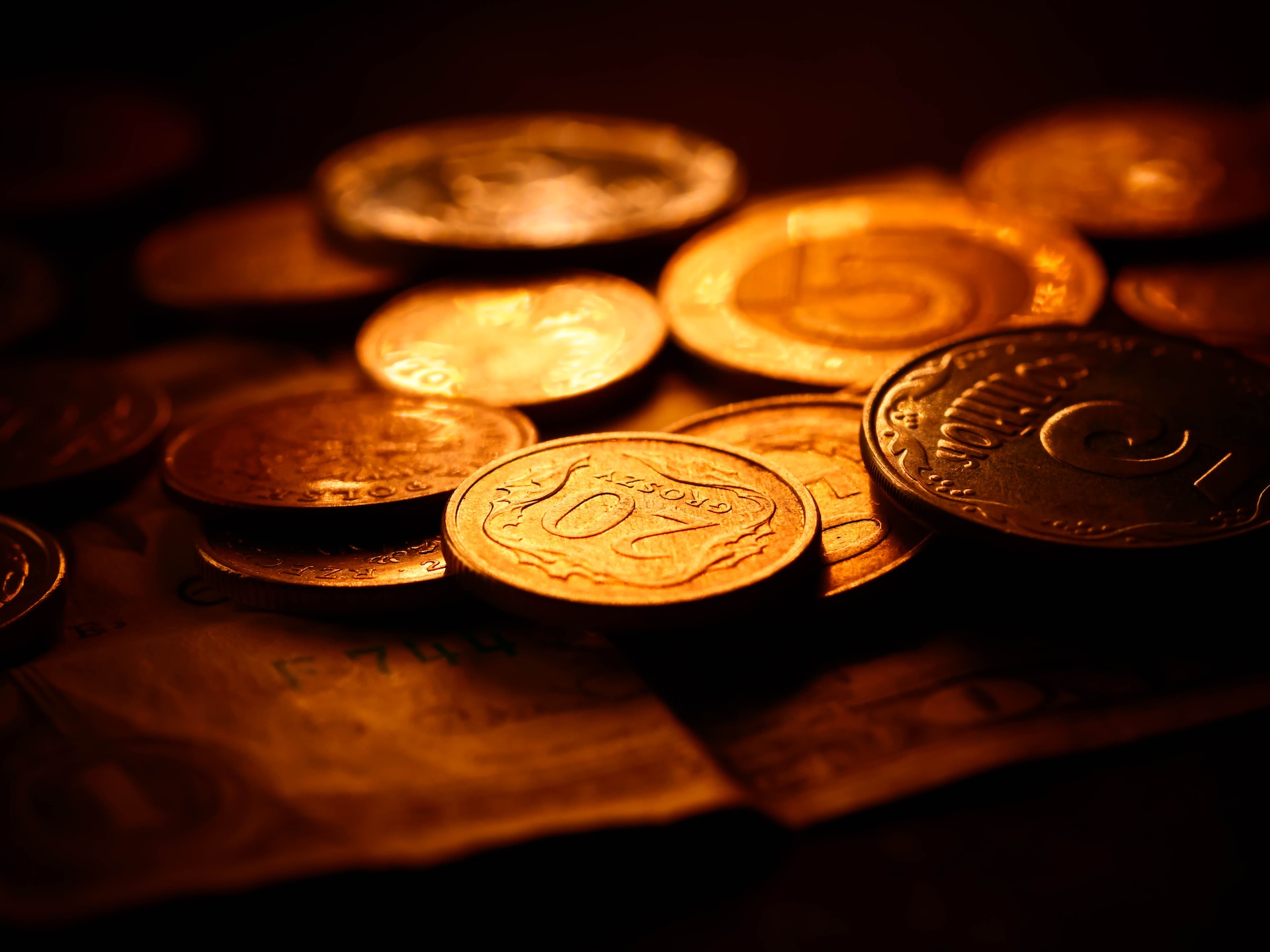 Dark photo of golden coins and money placed on a desk