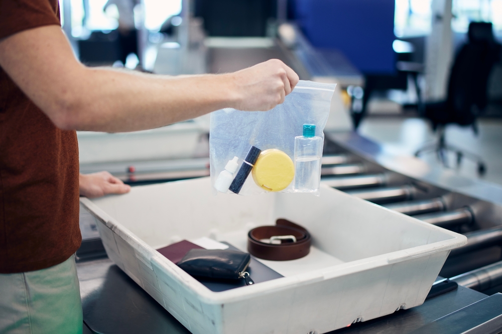 Passenger holding plastic bag with liquids above container personal items