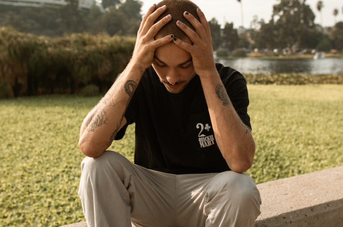 Young man is sitting and looking disappointed.